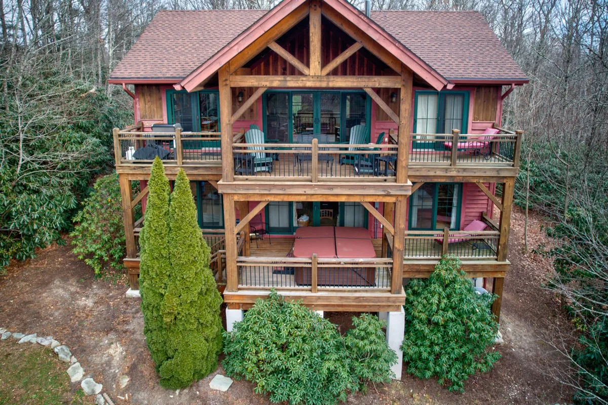A broad view of the lodge’s wooden structure, featuring balconies and surrounded by serene greenery. The spacious porch and balconies invite relaxation after exploring, hinting at pet-friendly outdoor spaces and social gatherings under the open sky.
